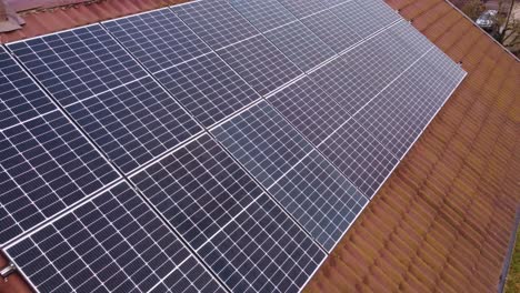 High-power-solar-panels-on-mossy-rooftop,-close-up-aerial-view