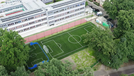 Right-orbiting-aerial-shot-of-a-brand-new-soccer-field-and-running-track-next-to-the-elementary-school-in-Poland,-4K-drone