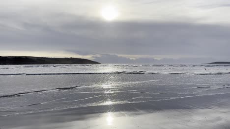 Silberne-Wellen-An-Einem-Sandstrand-Im-Winter-Mit-Sonne-Schimmern-Silbernes-Licht-In-Irland