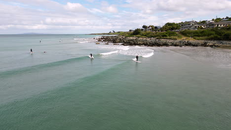 Vista-Aérea-De-Dos-Surfistas-Aprendiendo-A-Surfear-En-La-Playa-De-Riverton,-Nueva-Zelanda