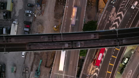 Slowly-Rising-Aerial-Shot-Over-Trains-Crossing-Over-Busy-Traffic-Conjunction-of-Commuting-Trucks-and-Cars