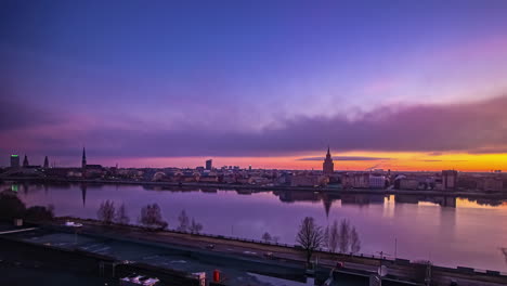 Increíble-Lapso-De-Tiempo-Que-Va-Del-Día-A-La-Noche-Y-La-Ciudad-De-Riga-En-Letonia-Se-Refleja-En-El-Agua