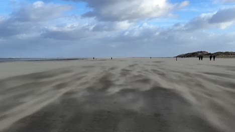 Sturm-An-Der-Küste,-Menschen-Laufen-Am-Strand-Durch-Den-Flugsand