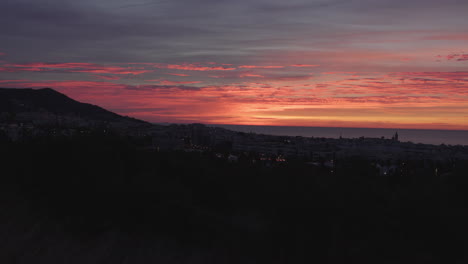 A-time-lapse-of-a-sunrise-over-the-horizon-of-the-sea,-mountains,-and-city