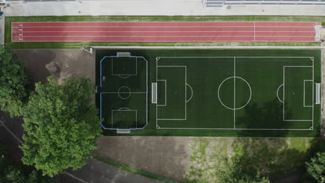 Aerial-top-down-shot-of-a-brand-new-soccer-field-and-running-track-next-to-the-elementary-school-in-Poland,-4K-drone