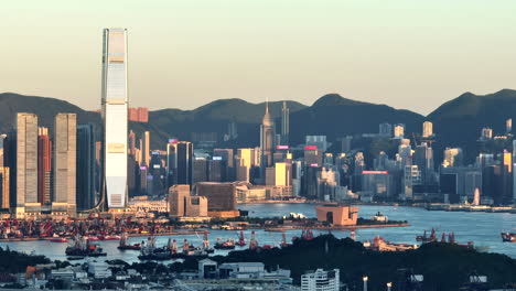High-skyline-of-Hong-Kong-city-illuminated-by-the-setting-sun-among-the-high-mountains-of-green-nature