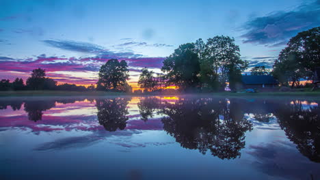 Stunning-sunset-reflecting-off-a-lake-by-an-countryside-home---time-lapse