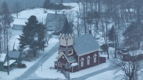 Wide-aerial-around-Swedish-Lutheran-Church-in-Monson-in-snow-blizzard