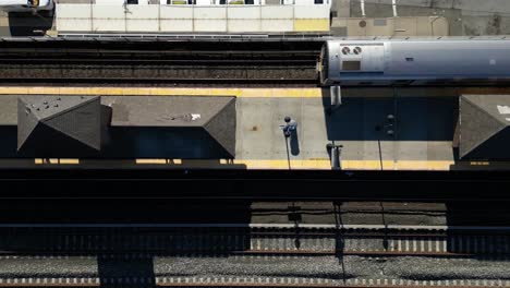 Ein-Blick-Von-Oben-Nach-Unten-Direkt-über-Einen-Bahnsteig,-Wenn-Ein-Zug-An-Einem-Sonnigen-Tag-Ankommt