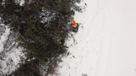 Aerial-Topdown-view-of-worker-with-chainsaw-clearing-fallen-trees-During-snowfall