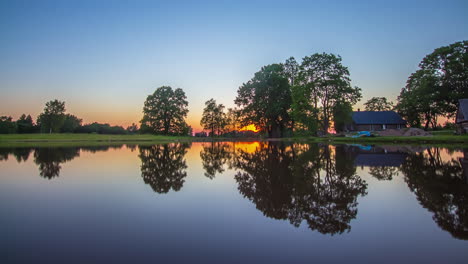 Time-lapse-of-a-sunset-at-lake-with-wooden-house-and-symmetrical-reflection