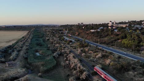 Tren-Local-Rojo-Que-Viaja-A-Lo-Largo-De-Los-Vehículos-Que-Circulan-Por-La-Carretera