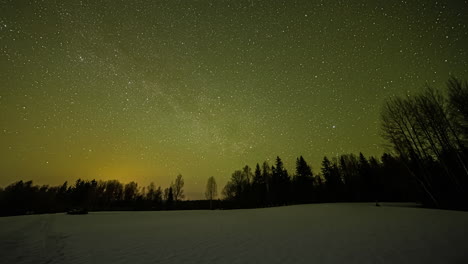 Magical-time-lapse-of-the-colorful-night-sky-filled-with-clear-stars-moving-above-a-snowy-winter-forest