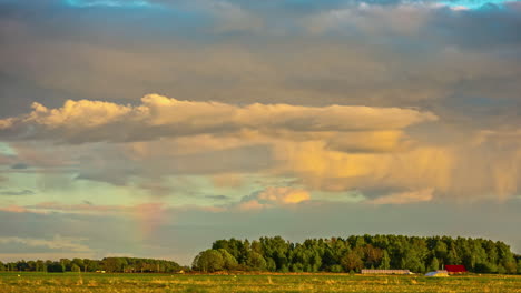 Grey-rain-clouds-forming-colorful-rainbow-on-sunny-day,-fusion-time-lapse