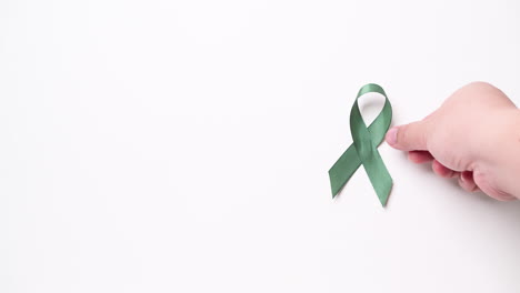 Detail-of-male-hand-putting-green-ribbon-over-white-background
