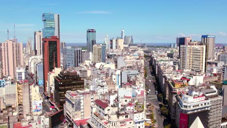 Dolly-in-aerial-view-of-wide-roads-in-downtown-Buenos-Aires,-with-disparate-buildings-on-a-sunny-day