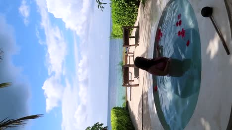 Vertical-shot-of-a-woman-standing-in-a-pool-alone-in-Zanzibar,-Tanzania