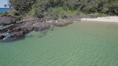 Mujer-Turista-Nadando-Sola-En-El-Mar-Durante-El-Verano-En-El-Punto-De-La-Isla-Doble-En-La-Playa-Del-Arco-Iris,-Cooloola,-Queensland