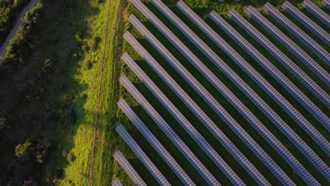 Top-down-aerial-view-of-Photovoltaic-Power-Station,-tilt-reveals-wind-turbine