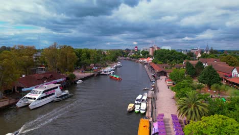 Dolly-in-aerial-view-of-the-Tigre-River-on-a-dramatic-day-full-of-clouds,-yachts-and-small-boats-navigating-the-channel
