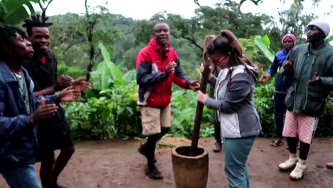 Afrikanischer-Chagga-Stamm,-Der-Einen-Touristen-Einlädt,-Arabica-Kaffeebohnen-Zu-Mahlen,-Während-Sie-Singen-Und-Tanzen