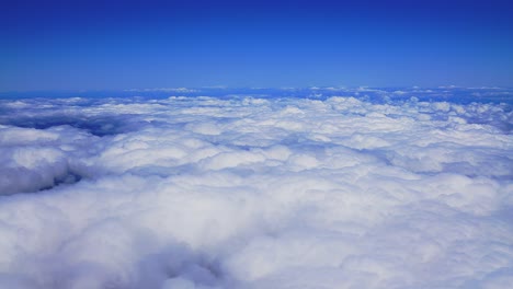 A-breathtaking-aerial-view-from-a-plane-as-it-glides-above-fluffy-white-clouds-amidst-the-bright-blue-sky-during-the-day