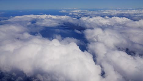 An-aerial-view-from-a-plane-captures-the-white-and-fluffy-clouds-during-the-bright-day