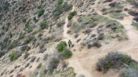 Aerial-rotation-view-of-a-male-hicker-walking-on-Deep-Creek-Trail-in-the-Hesperia-Desert-in-California