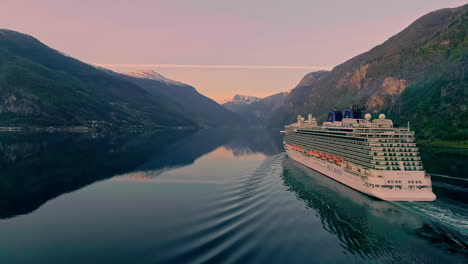 Aerial-view-of-P-and-O-cruise-ship-cruising-on-Fjord-between-mountains-during-purple-sunset-time-in-Norway