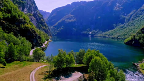 Beautiful-relaxing-view-of-mountains-over-shimmering-lake-with-green-vegetation-and-roadways
