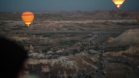 Aerial-POV-of-Cappadocia-at-Dawn-From-Hot-Air-Balloon,-Burners-and-Parachutes-Above-Scenic-Landscape