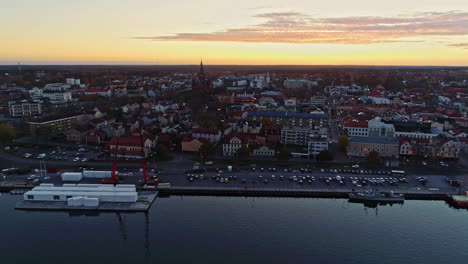 Aerial-backwards-shot-of-Slottsholmen-City-with-Church,-Old-Buildings-and-Waterfront-at-sunset