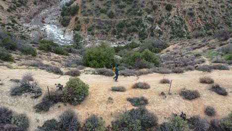 Aerial-follow-of-a-white-male-hiker-on-the-Deep-Creek-Trail-in-Hesperia-Desert,-California
