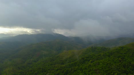 A-drone-shot-moves-forward-towards-a-tropical-mountain-valley-during-a-rainy-day,-slowly-entering-the-cloudy-mist-that-surrounds-the-peaks