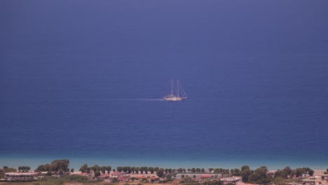 View-Of-Traditional-Sail-Boat-With-Mast-Off-In-Distance-In-The-Mediterranean-Sea-Off-Rhodes-With-Birds-Flying-Past