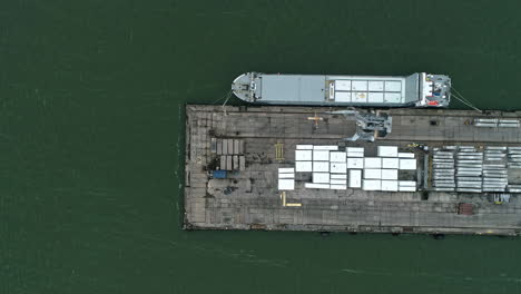 Aerial-view-of-loading-dock-shipping-containers-with-boat-anchored-waiting-to-be-loaded