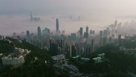 Rückwärts-Aufsteigende-Drohnenaufnahme-Von-Hongkong-City-Mit-Wolkenkratzergebäuden-über-Nebel-Am-Morgen