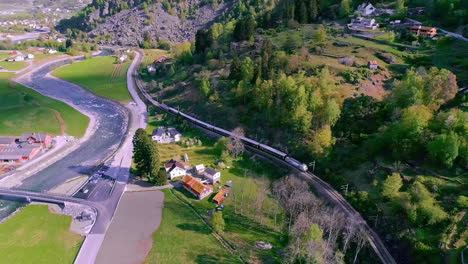 Beautiful-aerial-of-a-little-village-in-beautiful-Norwegian-mountains-and-nature-with-a-river-flowing-through-on-a-Sunne-day-in-Flåm