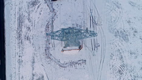 Flying-over-an-electrical-transmission-tower-in-winter---straight-down-flyover
