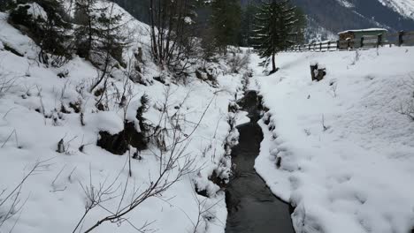 Drone-footage-flying-along-a-creek-in-the-snow-in-Austria
