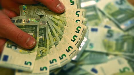 White-hands-efficiently-sorting-through-a-pile-of-5-Euro-bills,-Close-up