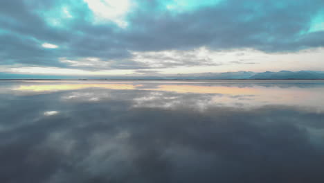 Surreale-Spiegelreflexion-Sonnenaufgang-Wolkengebilde-In-Ruhigem-Isländischen-Ozeanwasser
