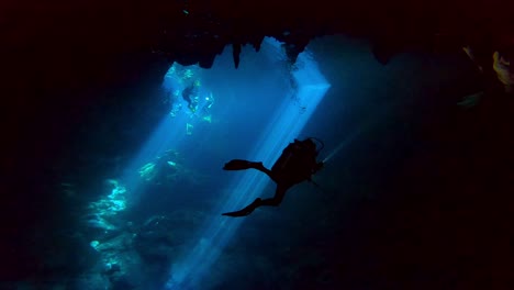 Silhouette-Eines-Tauchers-In-Einer-Höhle-Mit-Lichtstrahlen-Im-Hintergrund