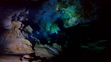 Diving-through-a-dark-underwater-cave-with-torches