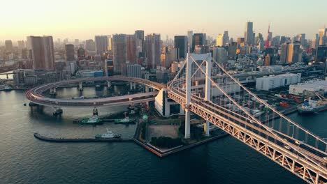Aerial-Drone-Shot-Of-Train-Loop-Near-Rainbow-Suspension-Bridge-in-Odaiba-Tokyo-City-Japan-With-Tokyo-Tower-in-the-Background