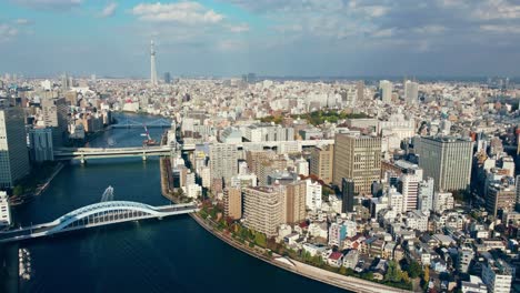 Aerial-Drone-Flying-Over-River-In-Tokyo-City-Japan-With-Tokyo-Skytree-In-The-Background