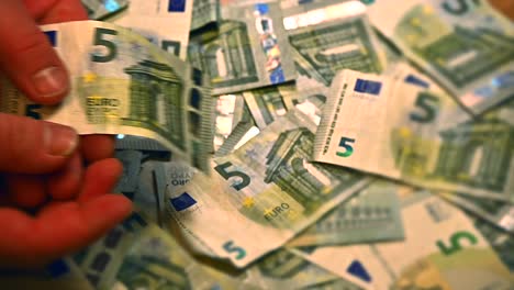Caucasian-hands-flipping-through-stacks-of-5-Euro-notes,-violently-ripped-out-of-their-grip-by-another-set-of-hands,-Close-up-perspective