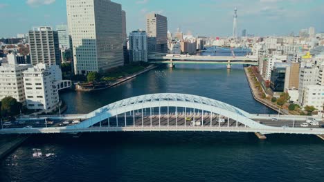 Aerial-Drone-Flying-Low-Over-Bridge-In-Tokyo-City-Japan-With-Tokyo-Skytree-In-The-Background
