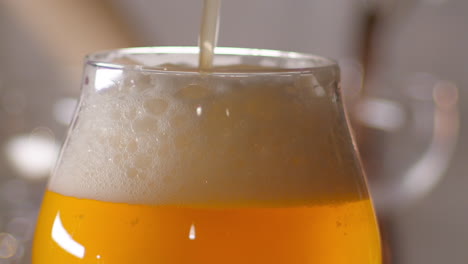 Zeitlupe-Nahaufnahme-Von-Craft-Beer,-Das-In-Ein-Tulpenglas-Gegossen-Wird,-Bar-Hintergrund