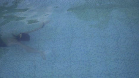Eine-Schlanke-Junge-Frau,-Die-In-Einem-Schwimmbad-Unter-Wasser-Schwimmt